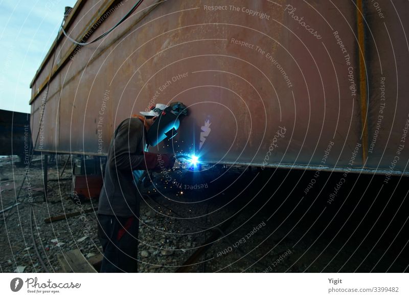 Welder Working in a Shipbuilding Yard assembly construction dock dockworker dockyard heavy industrial industry job laborer maintenance maritime metal nautical