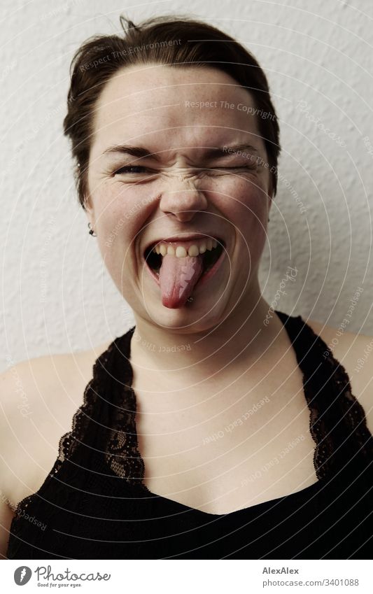 Portrait of a young woman - funny expression with tongue sticking out Uniqueness Looking into the camera Positive Happy Natural Colour photo brown eyes