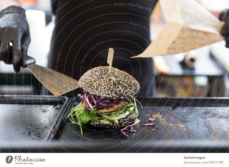 Chef preparing burgers at grill plate on international urban street food festival. hamburger meat fish man meal chef lunch cuisine bbq cooking flipping apron