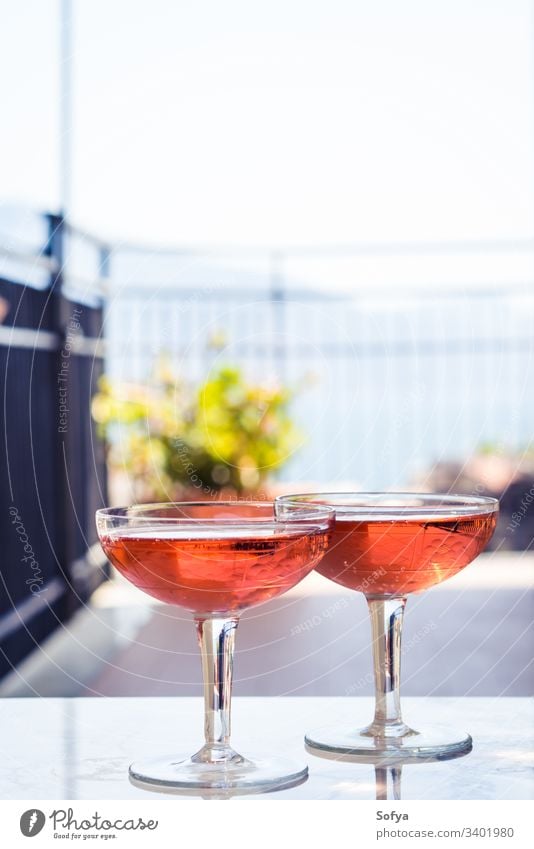 Two crystal stemmed glasses with rose wine outdoors on marble table. Aperitif time white party pink drink dinner luxury light background modern alcohol bar