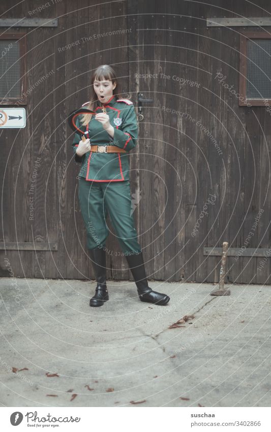 teenager in uniform wonders about the sharpness of the sickle she is holding in her hand ... and at the same time is a little worried she might hurt herself