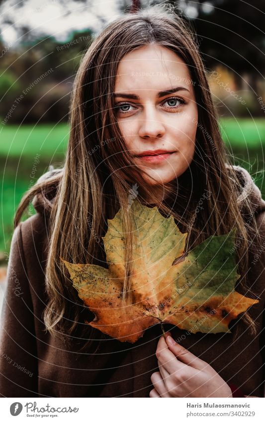 Beautiful girl holding a leaf with autumn colors moody woman portret brown clothed expresion face beauty nature fashion 20s