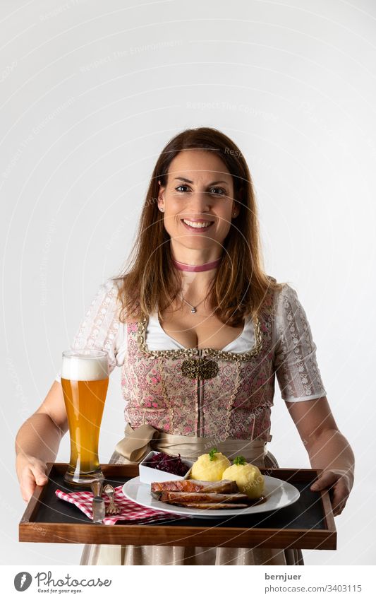 Woman in a Bavarian Dirndl with tray Dinner stop White segregated Oktoberfest Roast pork serve Carrying Alcoholic drinks Waitress Tray Costume Wheat beer