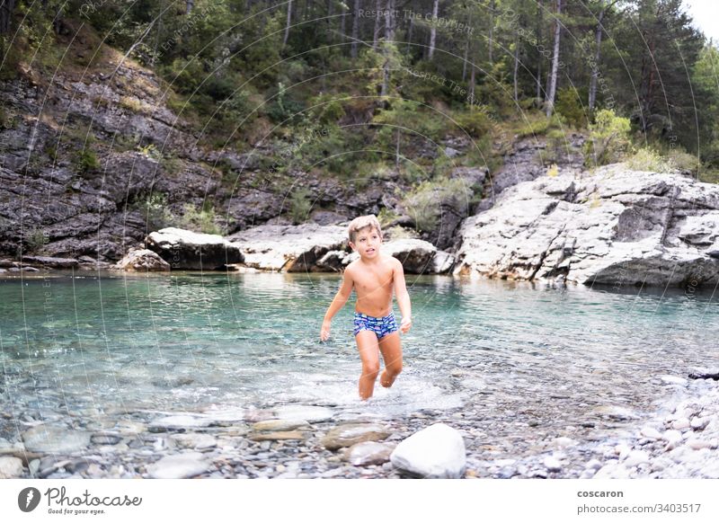 Little child in the middle of a wild river activity alone cheerful childhood cinca coast crossing day enjoyment flow fun game girl happiness healthy holidays