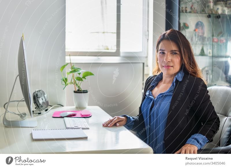 Executive woman in her office with large windows where the light enters. business businesswoman computer laptop young people sitting working desk smiling happy