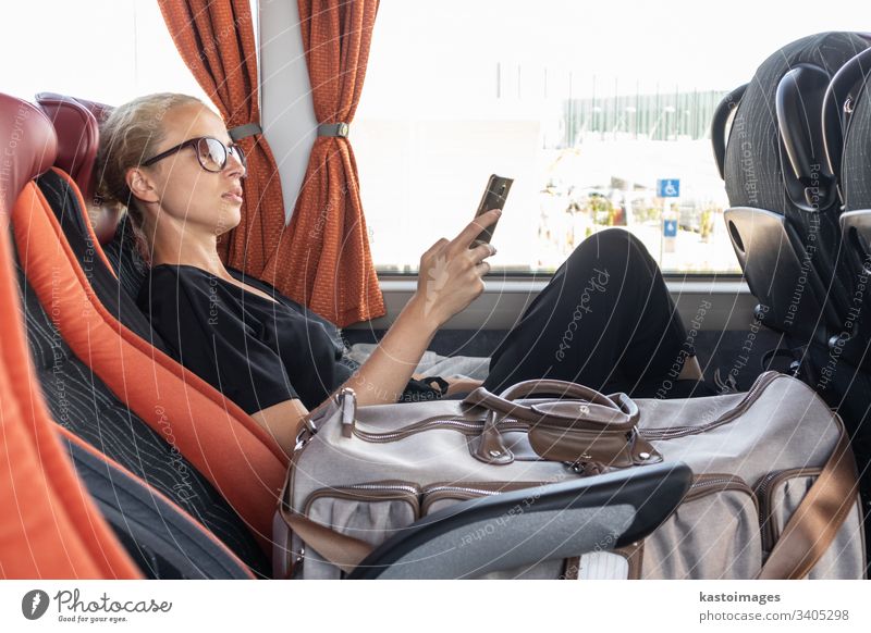 Portrait of woman driving on moving bus sitting by window using mobile phone. passenger female commuter girl transportation inside journey people person tired