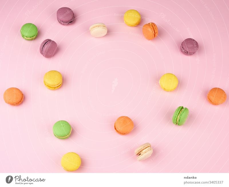 many multi-colored round baked macarons cakes on a light pink background almond assorted assortment bakery biscuit candy closeup colorful confection