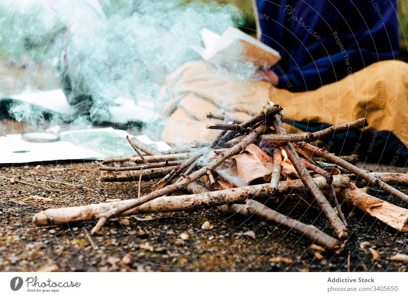 Young female backpacker making notes at campfire woman hiker write information trekking route rest bonfire countryside autumn nature environment adventure