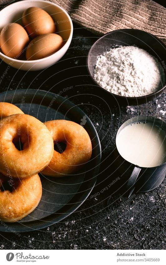 Doughnuts near ingredients on table doughnut cook kitchen recipe flour milk egg utensil pastry food napkin spoon tasty delicious bakery fresh sweet dessert