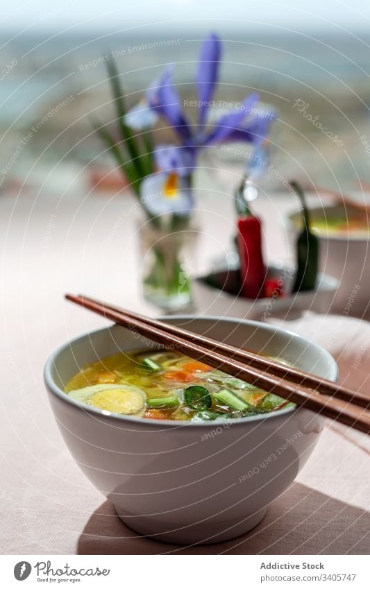 Oriental noodles soup in a restaurant food ramen asian chinese white vegan food vegetables vegetarian healthy food egg carrots onion spinach shiitake background