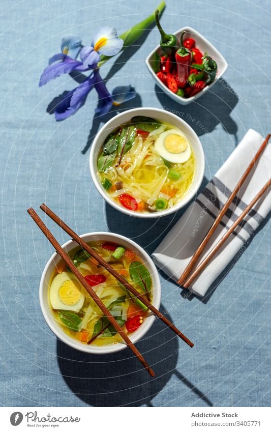 Oriental noodles soup in a restaurant food ramen asian chinese white vegan food vegetables vegetarian healthy food egg carrots onion spinach shiitake background