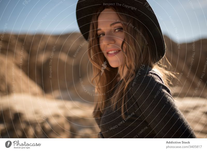 Trendy woman in dry desert style stone terrain countryside adjust hair bardenas reales navarre spain female eyes closed adventure nature hat journey travel