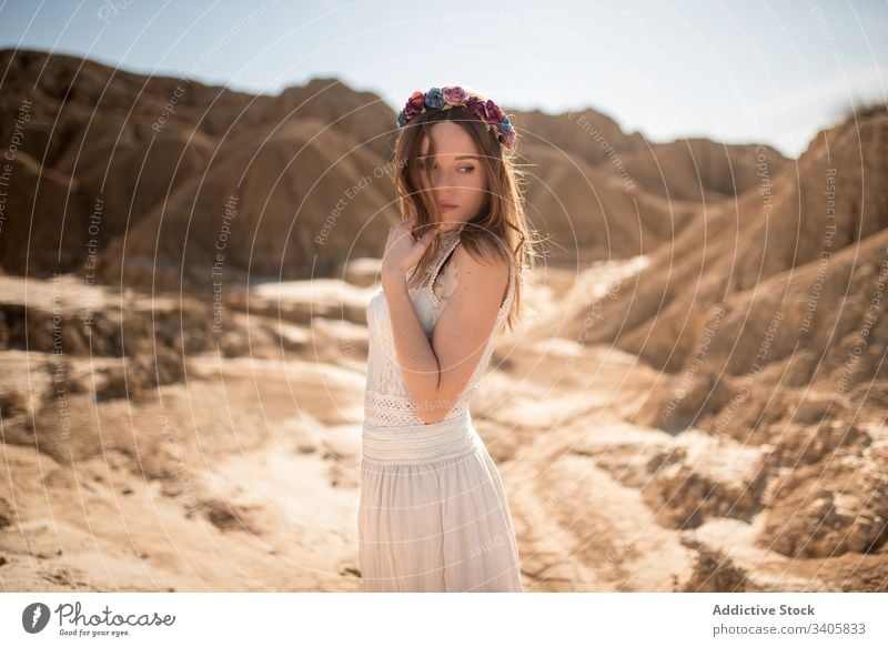 Elegant female in rocky terrain woman elegant countryside desert hill style sunny daytime nature bardenas reales navarre spain relax rest dress wreath trendy