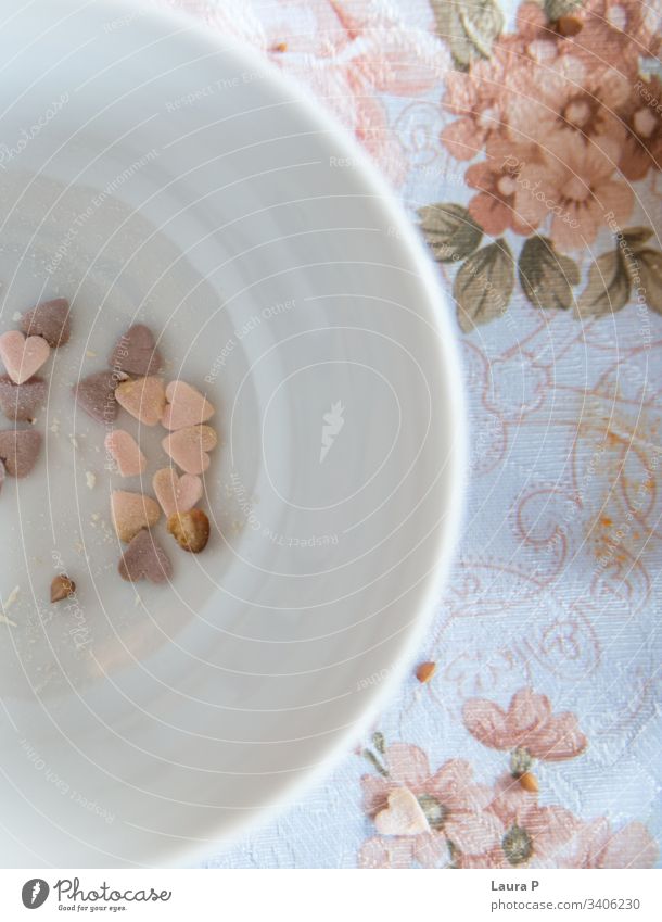 Heart shaped sweets in a white, round bowl, on a vintage table cloth hearts heart-shaped pink purple shabby chic floral flowers close-up concept decor