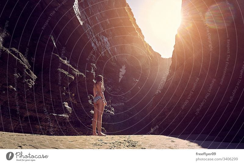 Young woman in bikini contemplating a rocky formation on a beach tourism hiking galicia spain ribadeo castros illas atlantic bay touristic cathedrals cliff