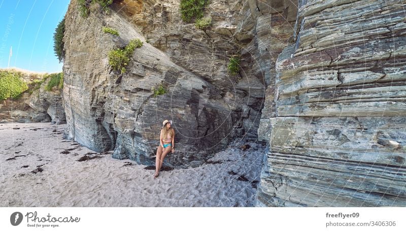 Young woman contemplating a cave made of rocks in Galicia, Spain tourism hiking galicia spain ribadeo castros illas atlantic bay touristic cathedrals cliff