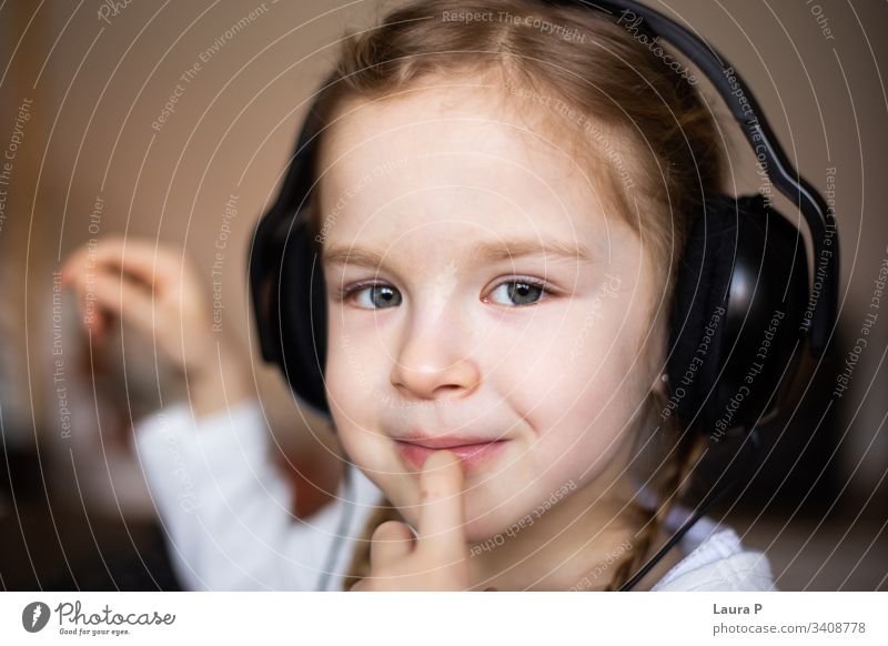 Close up of a beautiful blonde little girl listening to music at headphones smile happy young beauty child kid daughter fun cute enjoy isolated person