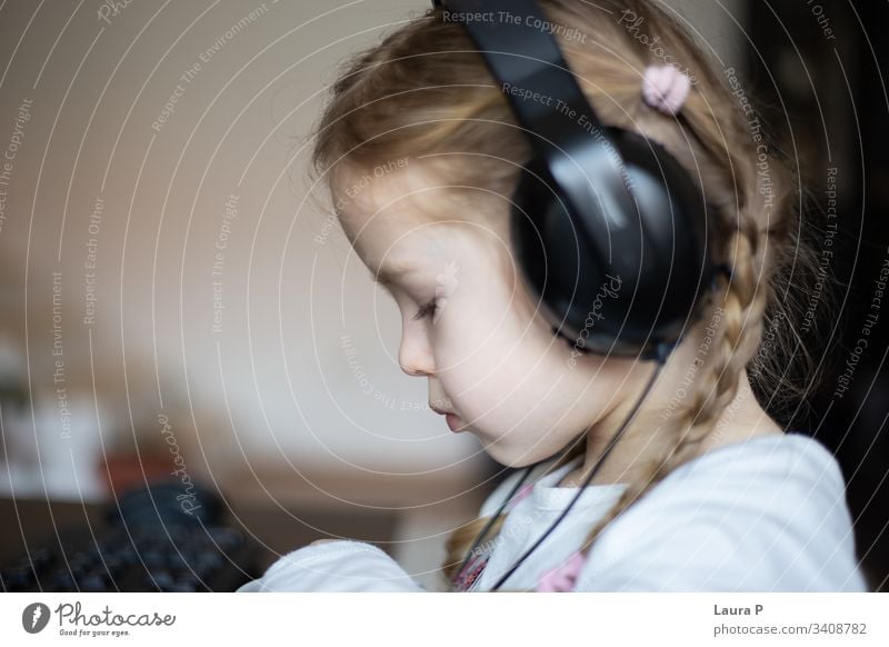 Close up of a beautiful blonde little girl listening to music at headphones smile happy young beauty child kid daughter fun cute enjoy isolated person