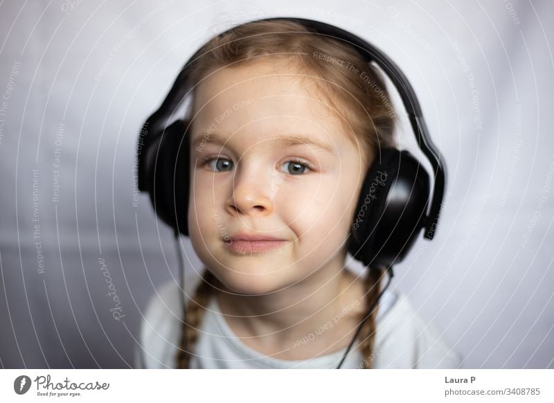 Close up of a beautiful blonde little girl listening to music at headphones smile happy young beauty child kid daughter fun cute enjoy isolated person