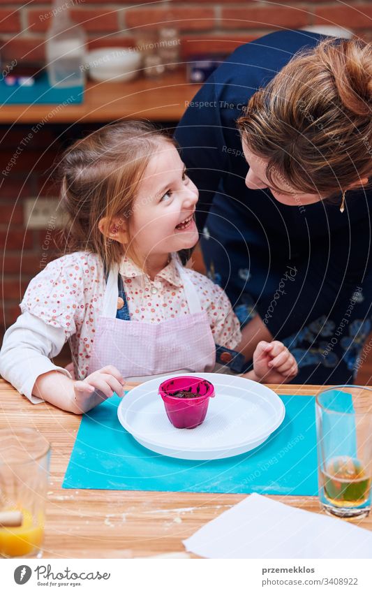 Happy satisfied little girl enjoying the muffin made by oneself. Taking part in baking workshop. Baking classes for children, aspiring little chefs. Learning to cook. Combining and stirring prepared ingredients. Real people, authentic situations