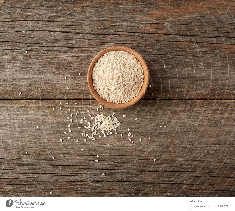 dry white sesame seeds in a brown wooden bowl food background organic ingredient healthy vegetarian closeup grain natural spice heap cooking condiment nutrition