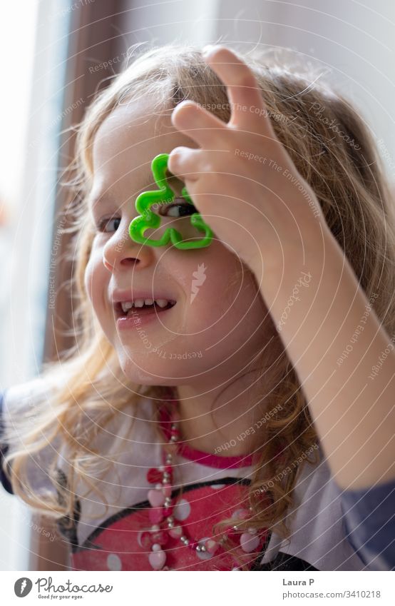 Happy little blonde girl looking through a dough shape sweet parenthood bonding emotion traditional celebration christmas cheerful assistant celebrate homemade