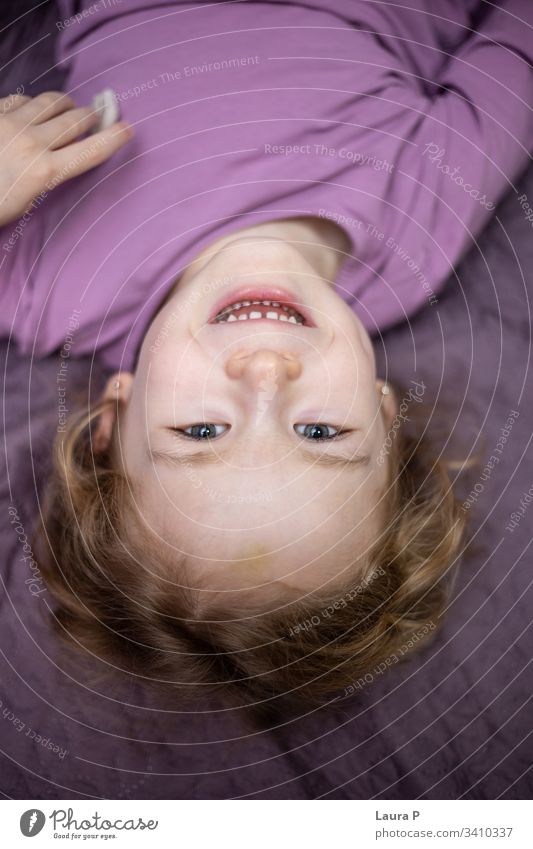 Happy little girl in pajamas, playing in bed down toddler laugh relaxation morning indoor preschool daughter adorable head face portrait bedroom bedtime upside