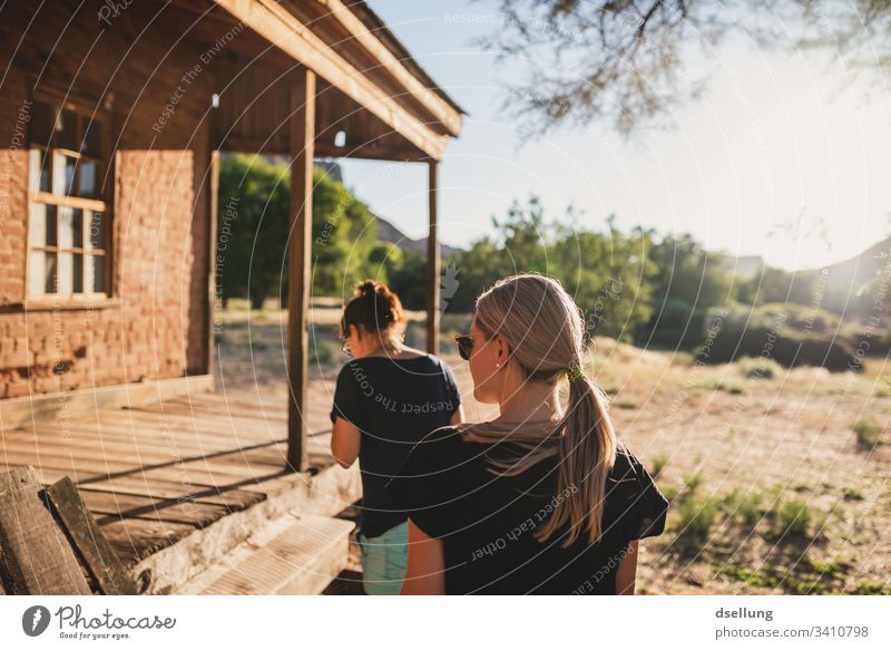 Two young women walk towards a wooden house in the evening light To enjoy recover relax Single-minded confident Future Forward Natural trees Plant Harmonious