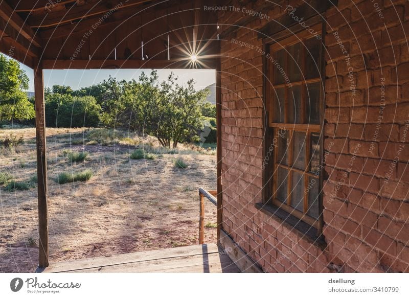 Brick house with wooden canopy in backlight Interior shot Calm straightforwardness Loneliness Deep depth of field Sun Ghost town Old Brown Tracks Back-light