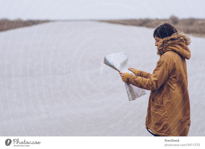 Woman reading a map next to a river, Greece. adventure search maps hands background beautiful female girl hiking holiday hood lake leisure looking nature