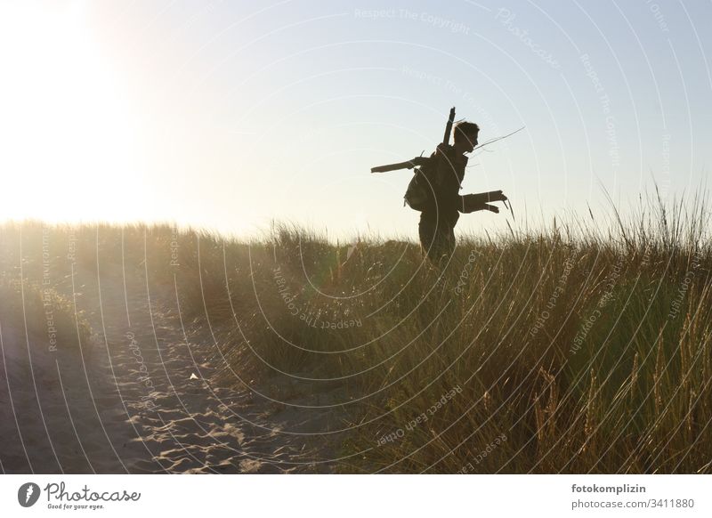 Silhouette of a young man in a beach dune firewood Vacation & Travel collect timber evening light Adventurer campfire Exterior shot Young man wanderlust