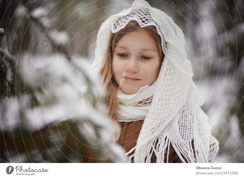 A 7 year old girl in a brown sheepskin coat  in the winter forest. Concept of the seasons, a winter fairy tale. Snow, trees. baby background beautiful beauty