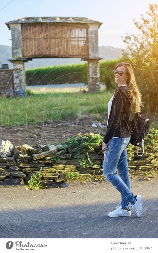 Young woman in front of a typical horreo in Galicia, Spain one 1 galicia galician agriculture old building rural tourism hiking north spaniard heaven roof tile