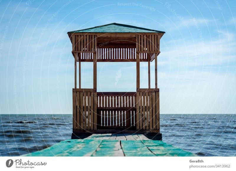 wooden arbor on the background of the sea and blue sky with clouds boards building gazebo nature old painted roof seascape surface water waves wooden gazebo