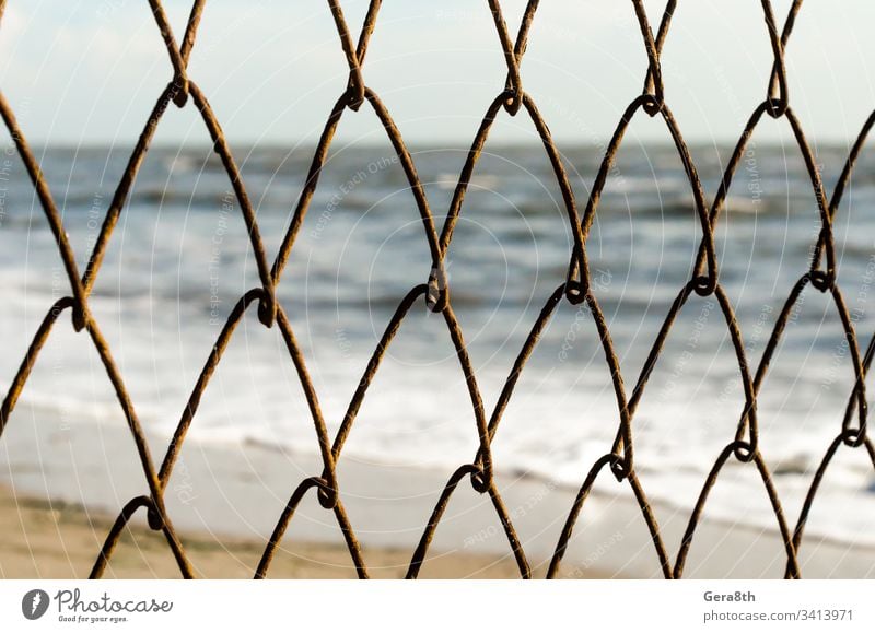 mesh wire fence on the background of the beach and the sea abstract blur blurred nature ocean repeating rust rusty sand sky surf water waves