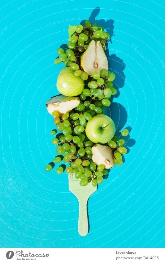 Composition with ripe grapes, pears, apples and brush colored green on blue background diet vegetarian fresh ingredient spring organic food plant colorful