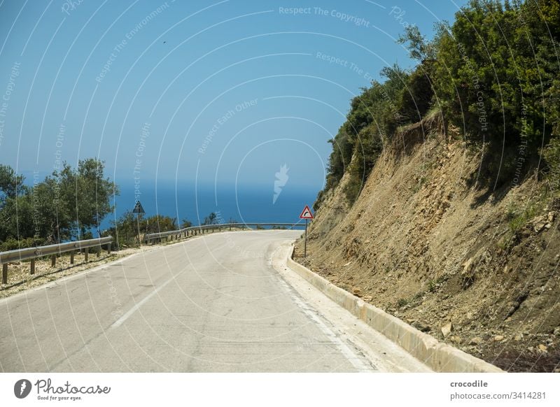 winding coastal road in Albania that branches off to the right Street Coast Right Curve Signs and labeling Concrete Old Ocean road trip bushes Asphalt Line