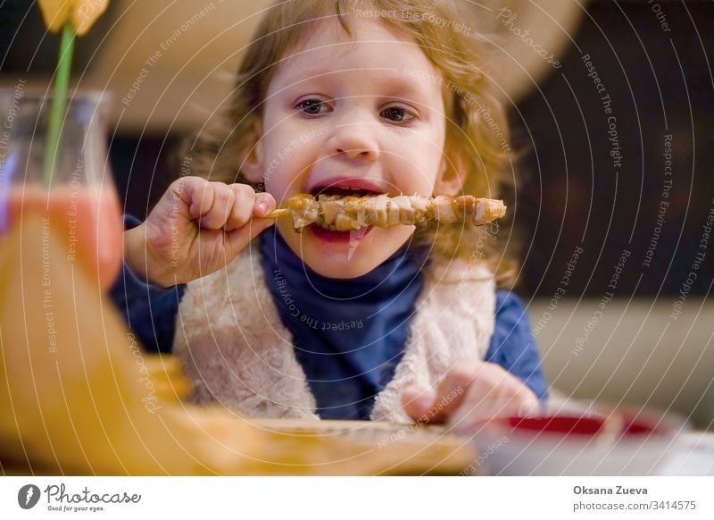 Little curly girl eating chicken in a cafe adorable baby caucasian child childhood children cute delicious dinner dinner in restaurant dinner restaurant enjoy