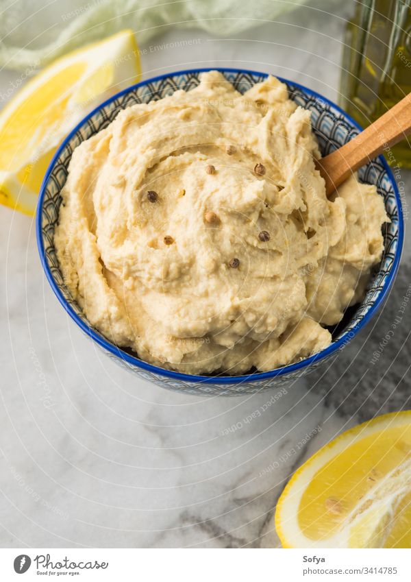 Mashed chickpeas Hummus dip in bowl hummus mashed tahini oriental vegan vegetarian healthy oil lemon garlic cumin blend sauce marble board cook spice Nutrition