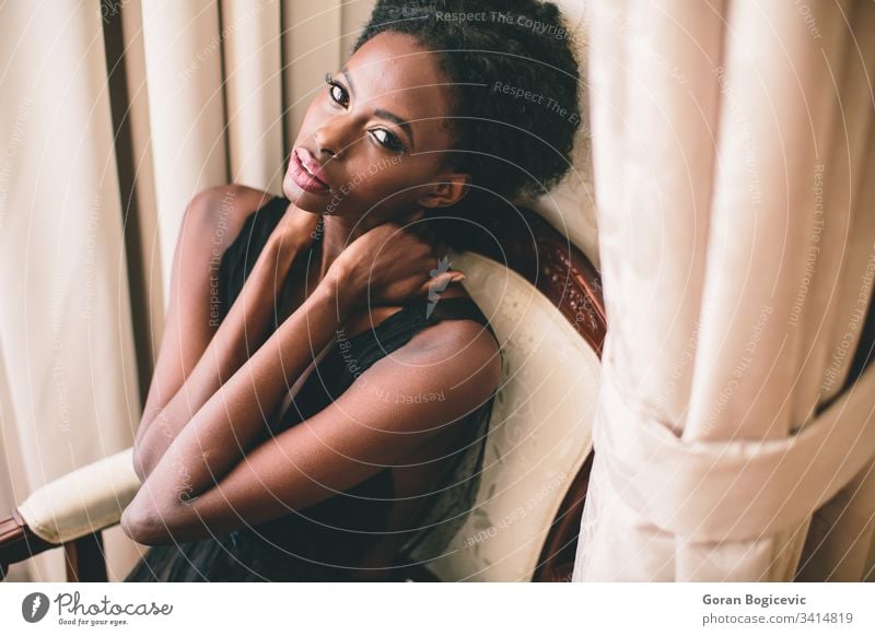 Young black woman in the room afro ethnicity calm adult sit female girl home american charming chair leisure attractive serenity curly relaxing cute modern