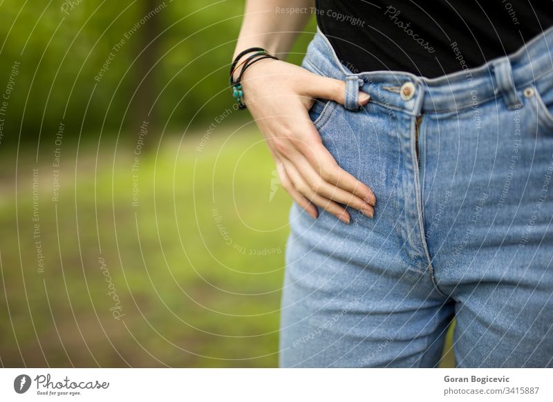 Woman in denim fit slim posing outdoor park fingers hands pants female jeans girl body young hips zip trousers size closeup dressing gettingdressed stomach