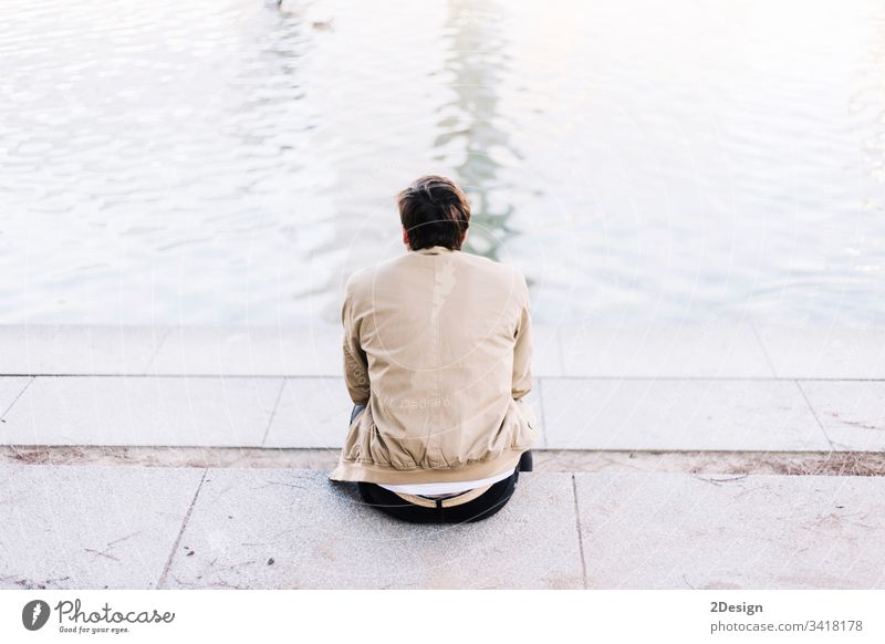 Handsome young man on lake in a sunny, peaceful day 1 person relaxation sky back casual attire attractive sitting photogenic male trendy white alone pier