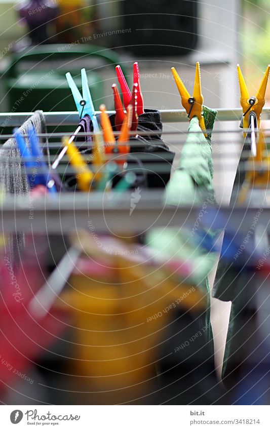 Colourful clothes pegs make the household and hang freshly washed laundry for drying on an outdoor clothes drying rack with shallow depth of field. Laundry