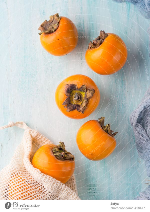 Ripe persimmons on turquoise background raw food fresh fruit winter autumn seasonal healthy ingredient ripe nutrition orange sweet asian exotic product japanese