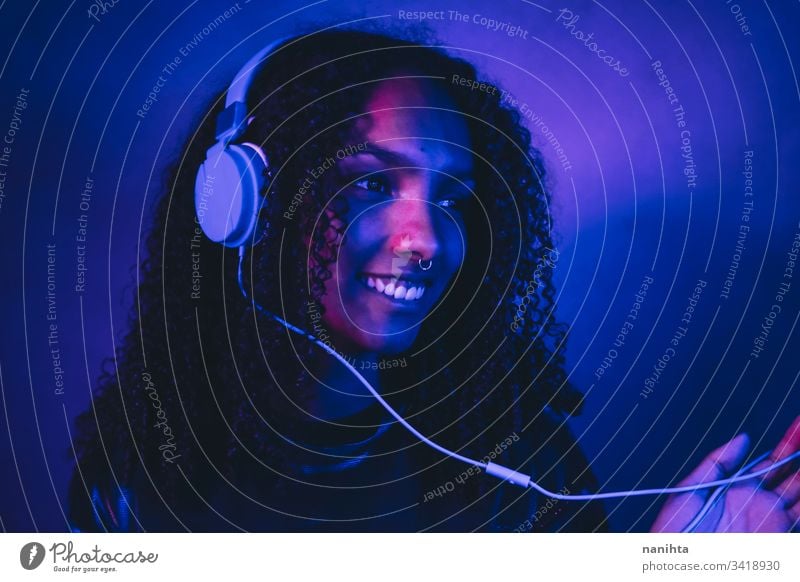 Artistic portrait with color lights of a young woman neon black art artistic cool afro afro american music headphones headset technology listening dj african