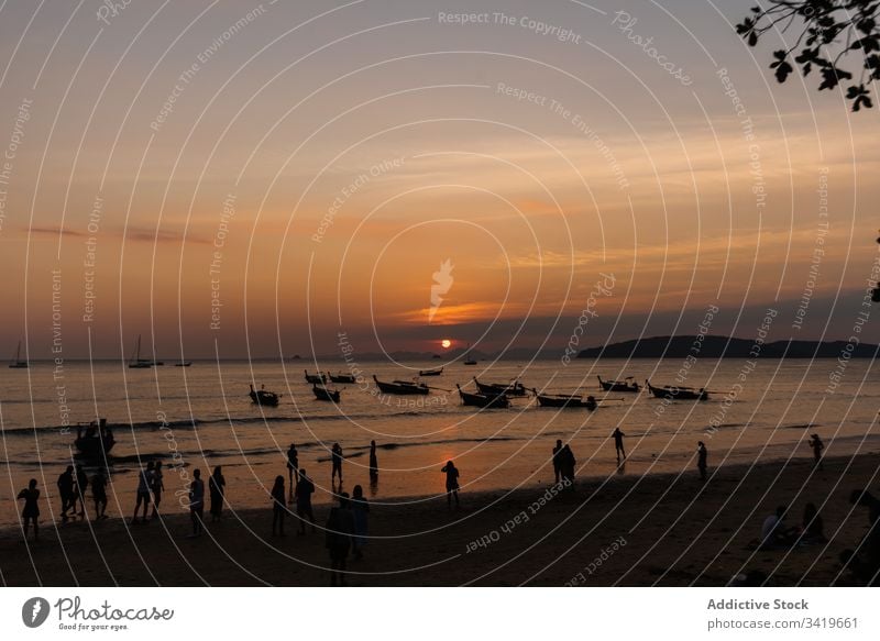 People on shore of ocean in evening sunset beach sea boat nature water travel vacation sky coast wave tropical paradise dusk vessel beautiful transport