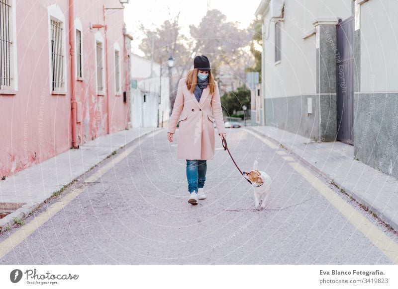 caucasian woman in the street wearing protective mask and walking with her dog. corona virus concept outdoors mobile phone technology internet public adult