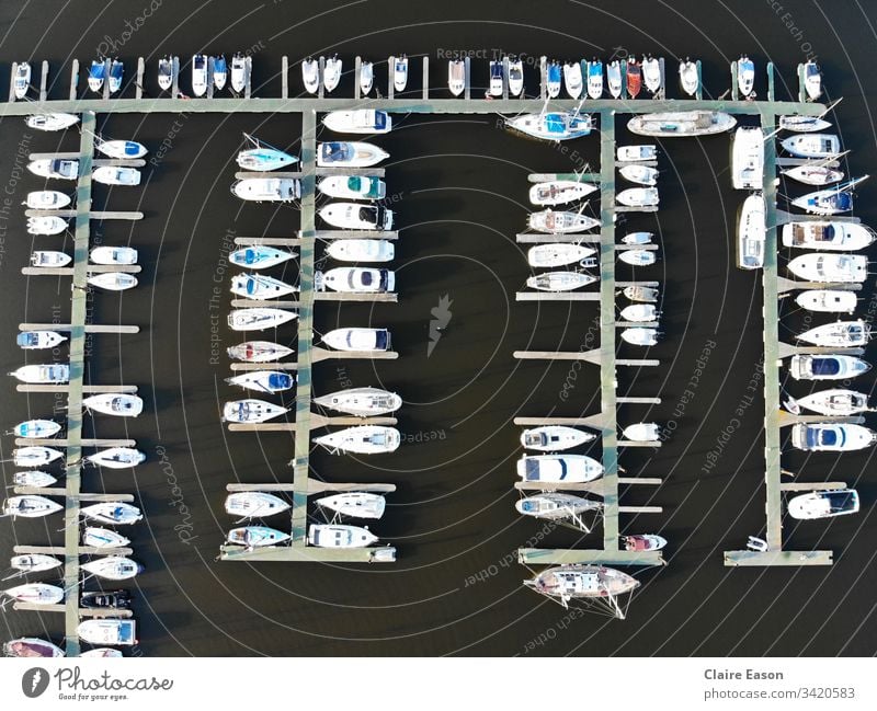 Aerial view of many boats docked in a marina, against dark water, created by dji camera. Marina sailing decks aerial view coastal seaside leisure nautical