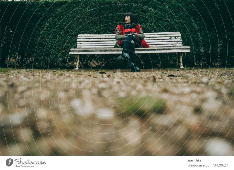 Young woman relaxing in a green park in winter outdoor solitude alone loneliness nature natural cold youth fresh real candid rest resting calm tranquiltiy