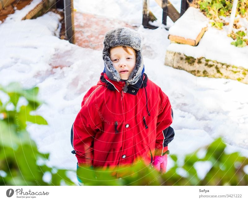 Little blonde boy in winter outerwear outdoors child snowsuit happy little look face eyes white caucasian kid cold hat cap cute fun season playing clothing